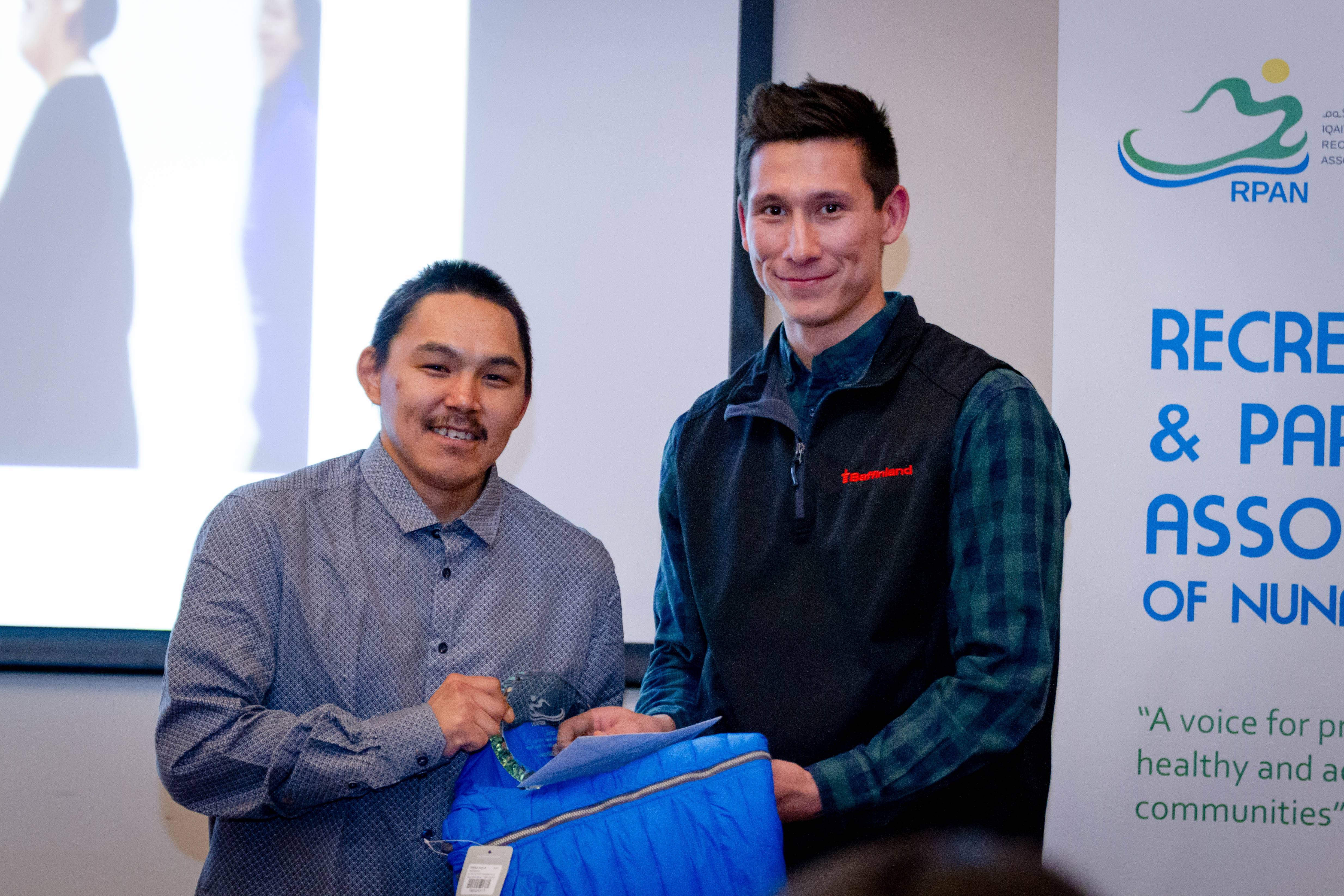 Devin Aviugana, assistant manager of Northern Affairs, presents Terry Killiktee of Clyde River with the Baffinland Iron Mines Recreation Leader of the Year award